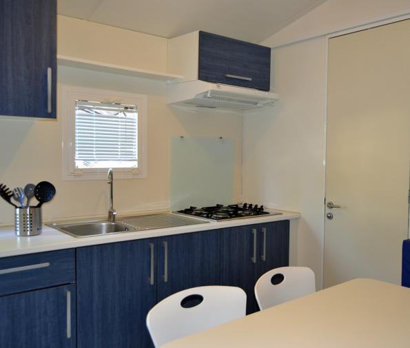 Modern kitchen with blue cabinets, sink, stove, and white table.