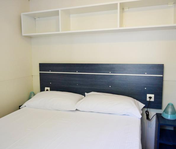 Minimalist bedroom with a double bed and wall shelves.