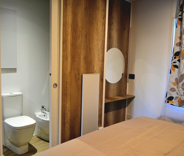 Bedroom with private bathroom, floral curtains, and wooden decor.