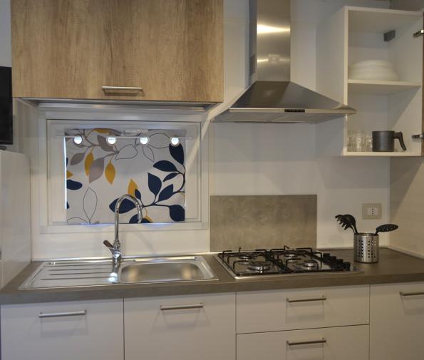 Modern kitchen with gas stove, hood, and stainless steel sink.