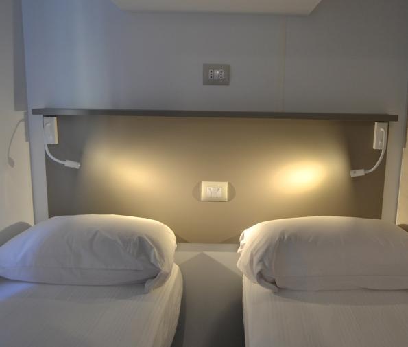 Two single beds with reading lights and switches on the headboard.